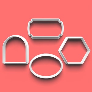 Op de afbeelding: Set van vier witte plastic koekjesvormen in verschillende vormen: ovaal, rechthoek met afgeronde hoeken, boog en zeshoek.