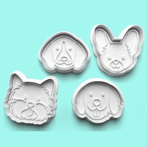May include: Four white plastic dog-shaped cookie cutters. The set includes a beagle, a French bulldog, a fluffy dog, and a golden retriever. The cutters are on a light blue background.