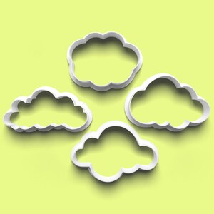 Può includere: Quattro formine bianche a forma di nuvola su sfondo verde chiaro. Le formine hanno forme e dimensioni diverse, con bordi arrotondati e un design pulito. Ideali per la pasticceria.