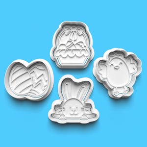 Puede incluir: Cuatro cortadores de galletas de plástico blanco con forma de cesta de Pascua con un huevo dentro, un conejito, un pollito y dos huevos de Pascua.