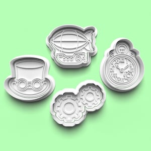 Può includere: Quattro formine per biscotti in plastica bianca a tema steampunk. Le forme includono un cappello a cilindro con occhiali, un dirigibile, un orologio da tasca e due ingranaggi ad incastro. Sfondo verde chiaro.