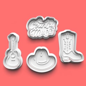 May include: Four white cookie cutters on a pink background. The shapes include a guitar, a cowboy hat, a cowboy boot, and a cloud-shaped cutter with the words "Country Music" in script.
