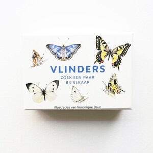 May include: A box with a blue and white butterfly illustration on the front. The box says "VLINDERS" in blue letters and "ZOEK EEN PAAR BIJ ELKAAR" in black letters. The box also has illustrations of other butterflies in yellow, white, and brown.