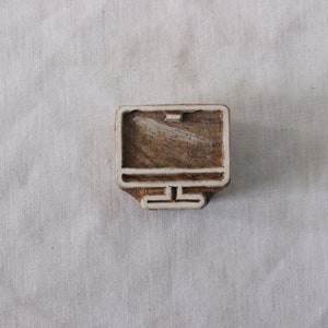 May include: A wooden block printing stamp shaped like a computer monitor. The stamp is made of light brown wood with a white outline.