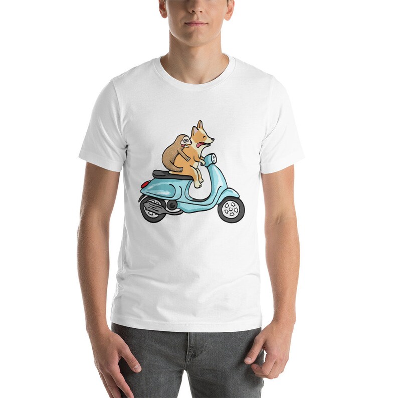 May include: A white t-shirt with a cartoon image of a corgi and a sloth riding a blue scooter.