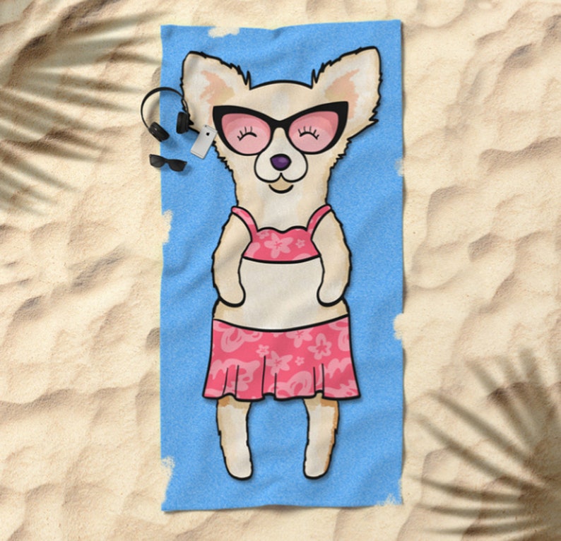 May include: A white chihuahua wearing pink sunglasses and a pink floral bikini is lying on a blue beach towel.