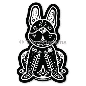 May include: Black and white illustration of a French bulldog with a Day of the Dead sugar skull design. The dog is sitting with its legs crossed and has a floral pattern on its body.