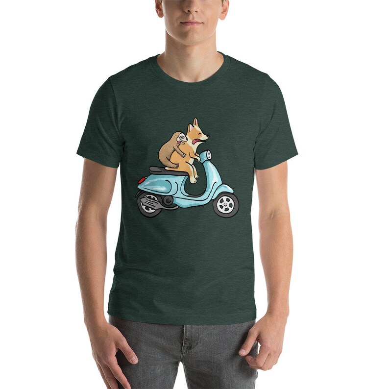 May include: A green t-shirt with a cartoon image of a corgi and a sloth riding a blue scooter.
