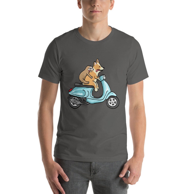 May include: A dark gray t-shirt with a cartoon illustration of a corgi and a sloth riding a blue scooter.