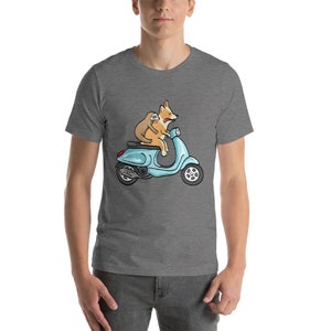 May include: A gray t-shirt with a cartoon illustration of a corgi and a sloth riding a blue scooter.
