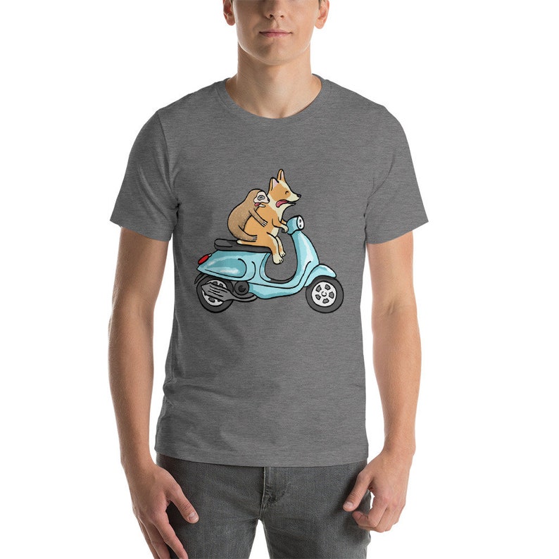 May include: A gray t-shirt with a cartoon illustration of a corgi and a sloth riding a blue scooter.