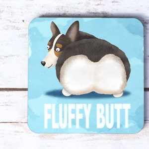 May include: Square coaster featuring a cartoon corgi dog with its rear end facing the viewer. The dog is black, white, and brown, set against a light blue background with the words "FLUFFY BUTT" in white. The coaster is likely made of ceramic.
