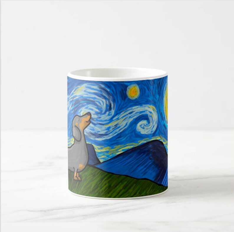 Op de afbeelding: Een witte keramische koffiemok met een blauwe en gele schildering van een teckel die omhoog kijkt naar een sterrenhemel. De schildering doet denken aan het werk van Vincent van Gogh, "De Sterrennacht".