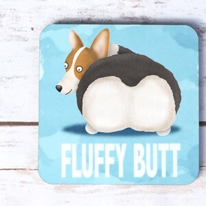 May include: Square coaster featuring a cartoon corgi dog with its fluffy rear end facing the viewer. The dog is brown, white, and black, set against a light blue background with the words "FLUFFY BUTT" in white.