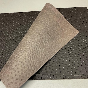 May include: A close-up of two pieces of textured leather. One piece is a dark brown, and the other is a lighter tan color. Both pieces have a pattern of small, evenly spaced holes.