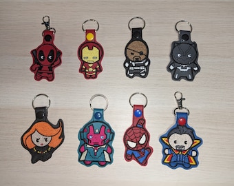 May include: Set of 10 keychains featuring different Marvel characters. The keychains are embroidered with colorful designs of characters like Deadpool, Iron Man, Black Widow, and more. Each keychain has a metal ring for attaching to keys or bags.