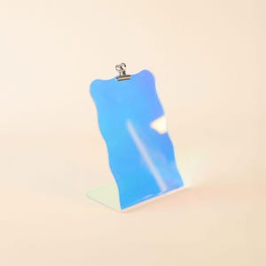 May include: A blue iridescent acrylic clipboard with a wavy edge and a silver clip.
