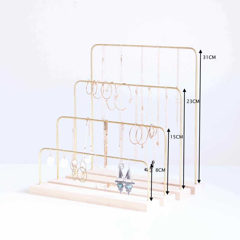 Pode incluir: Suporte de joias de metal dourado com tr&ecirc;s n&iacute;veis para colares e brincos. O suporte mede 31 cm de altura, 23 cm de largura e 8 cm de profundidade. Tem uma base de madeira.