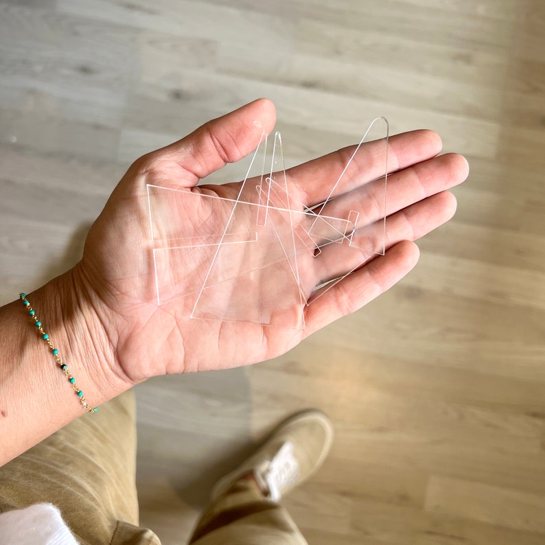 K&ouml;nnte beinhalten: Eine Hand h&auml;lt einen Satz durchsichtiger Acryl-Pr&auml;sentationsst&auml;nder. Die St&auml;nder sind in verschiedenen Formen und Gr&ouml;&szlig;en und eignen sich perfekt zum Pr&auml;sentieren kleiner Gegenst&auml;nde.