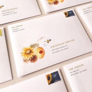 May include: White envelopes with gold lettering and a watercolor illustration of sunflowers, honeycombs, and bees. The text on the envelopes reads "Lori Palmisano", "The Smiths", and "Savannah Greene".