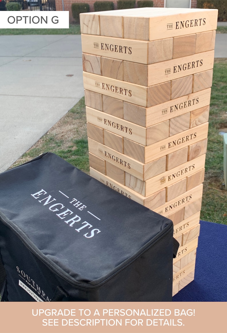 Puede incluir: Un juego de apilamiento de bloques de madera con el nombre "THE ENGERTS" impreso en cada bloque. Una bolsa de transporte negra con el mismo nombre est&aacute; en primer plano. El texto "UPGRADE TO A PERSONALIZED BAG! SEE DESCRIPTION FOR DETAILS." est&aacute; en la parte inferior.