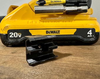 May include: A yellow and black DeWalt 20V Max 4Ah battery with a black plastic mounting bracket. The battery has a DeWalt logo and a black and yellow DeWalt screwdriver bit holder attached to the top.