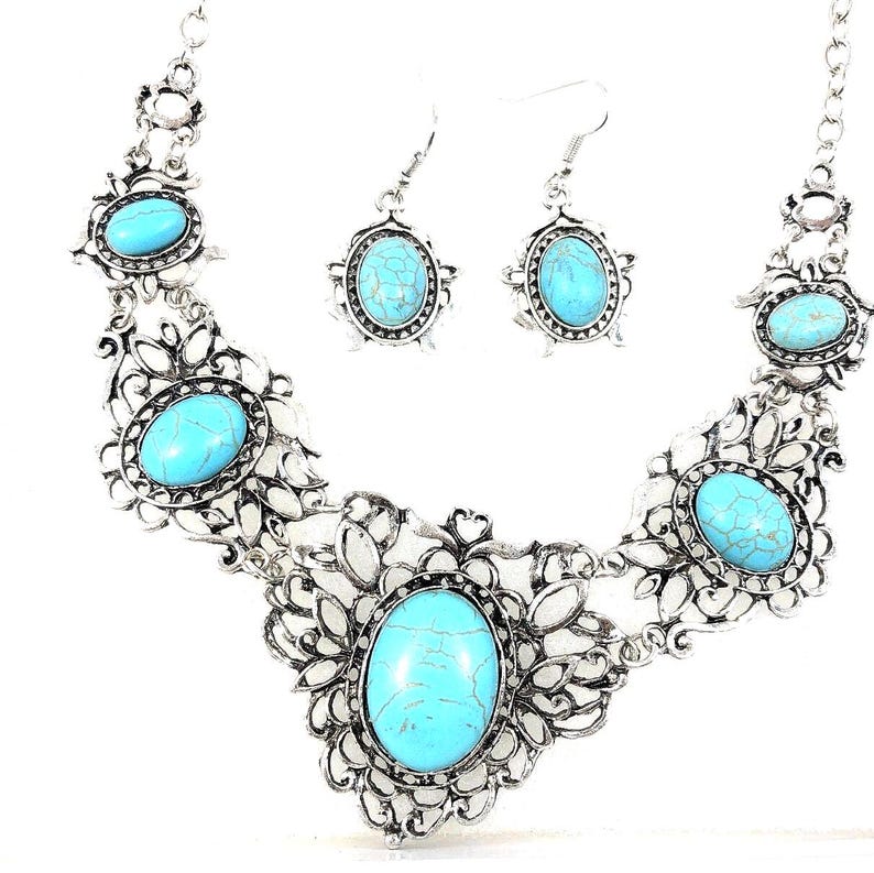 close-up shot of filigree turquoise necklace and earring set, antique silver color, for women.