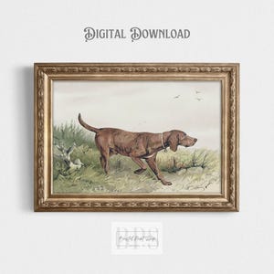 Op de afbeelding: Een ingelijste prent met een bruine hond die door een veld rent. De prent heeft bovenaan de tekst "DIGITALE DOWNLOAD". De hond bevindt zich in een grasrijk gebied, met een lichte lucht en vogels op de achtergrond. De lijst is goudkleurig.