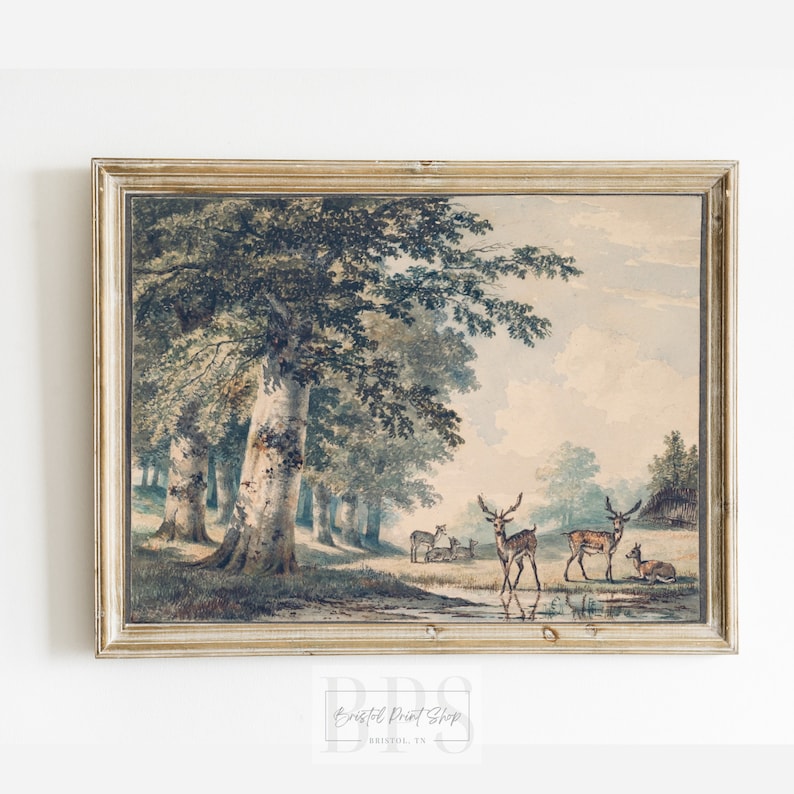 Puede incluir: Una pintura de acuarela vintage en un marco de madera claro representa una escena de bosque con un grupo de ciervos de pie en un claro. Los ciervos son marrones y blancos con cuernos. El bosque es exuberante y verde con un arroyo que lo atraviesa. El cielo es de un azul suave con nubes blancas.