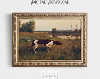 Op de afbeelding: Een ingelijste vintage-stijl print met een bruin-witte hond in een veld, met een waterpartij op de achtergrond. Het kunstwerk is geplaatst in een goudkleurige, sierlijke lijst. De woorden "DIGITALE DOWNLOAD" staan bovenaan.