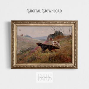 May include: A vintage painting depicting two hunting dogs in a field. The dogs are a black and brown pointer and a white and brown pointer. The dogs are standing in a field of green grass and wildflowers. The painting is framed in a gold frame.