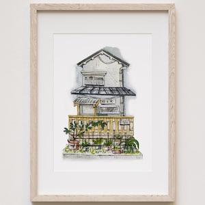 May include: Watercolor illustration of a Japanese building with a wooden fence and potted plants. The building is white with a dark roof and a sign in Japanese. The artwork is framed in a light wood frame.