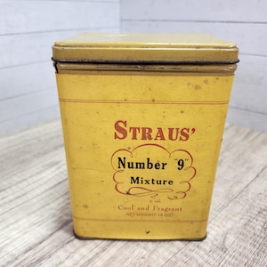May include: Vintage yellow metal tin with a rectangular shape and a removable lid. The tin features the text "STRAUS' Number '9' Mixture" in red lettering. The bottom of the tin reads "Cool and Fragrant NET WEIGHT 14 oz."