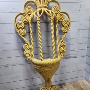 May include: A yellow plastic wall planter with a woven design. The planter has a basket-like shape with a decorative top.