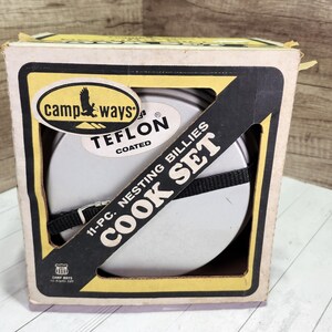 May include: A vintage Camp Ways Teflon-coated nesting billies cook set in its original box. The box is beige with black and yellow accents, and the cook set is secured with a black strap. The text "COOK SET" is prominently displayed.