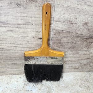 May include: A vintage paint brush with a wooden handle and black bristles. The handle is labeled "Buster".