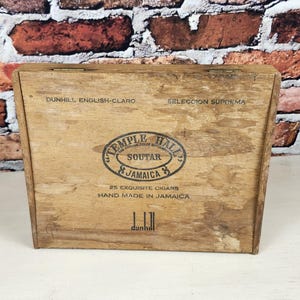 May include: A rectangular wooden cigar box with a light brown finish. The lid features black printed text reading Temple Hall, Soutar, Jamaica, 25 Exquisite Cigars, Hand Made In Jamaica, Dunhill English-Claro, Seleccion Suprema, and the Dunhill logo.