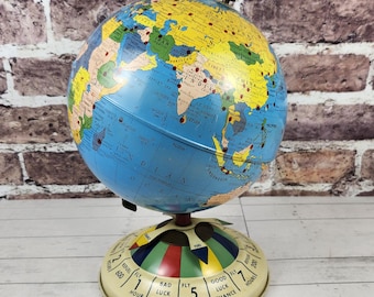 May include: A vintage globe with a blue ocean and yellow continents, mounted on a cream-colored base. The base features a dial with the text "BAD LUCK" and "GOOD LUCK". The globe is a decorative item.
