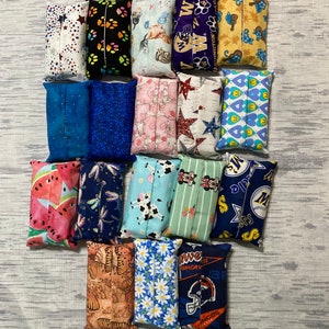 May include: A collection of 15 colorful tissue box covers with various patterns and designs. The covers are made of fabric and feature themes such as sports, animals, and abstract designs.