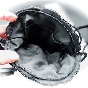 Puede incluir: Bolso de noche negro con cuentas, con cierre de cremallera y asa de cuerda negra. El bolso est&aacute; forrado con tela negra y tiene un peque&ntilde;o bolsillo en el interior.