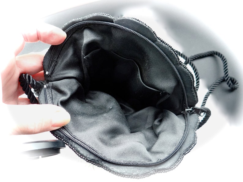 Puede incluir: Bolso de noche negro con cuentas, con cierre de cremallera y asa de cuerda negra. El bolso est&aacute; forrado con tela negra y tiene un peque&ntilde;o bolsillo en el interior.