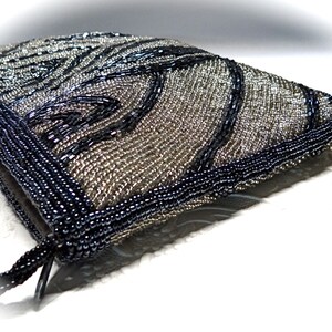 May include: A silver and black beaded evening bag with a black beaded strap. The bag features a geometric pattern.