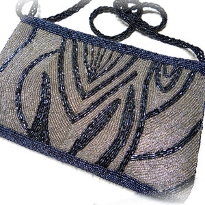 May include: A silver and black beaded evening bag with a geometric pattern. The bag has a long beaded strap.
