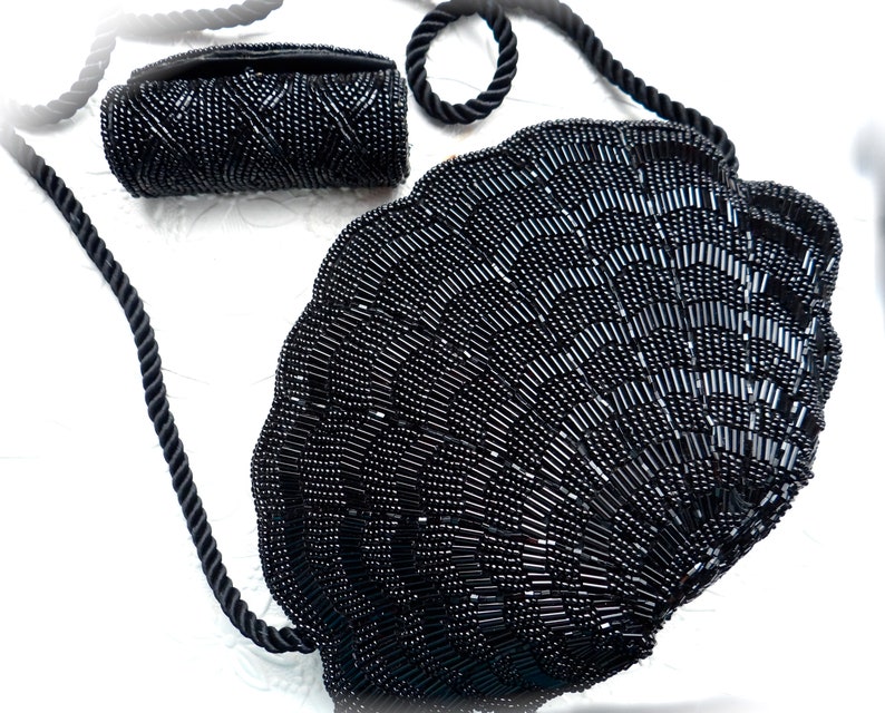 Puede incluir: Un bolso de noche negro de cuentas con forma de concha con un clutch de cuentas negras a juego.