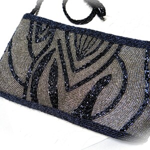 May include: A black and silver beaded evening bag with a geometric pattern. The bag has a black beaded strap.