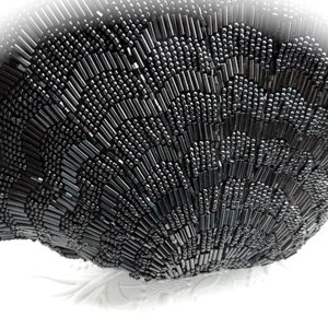 Puede incluir: Un bolso de noche negro de cuentas con un dise&ntilde;o redondeado en forma de abanico. El bolso est&aacute; hecho de peque&ntilde;as cuentas negras que est&aacute;n cosidas juntas en un patr&oacute;n.