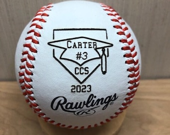 May include: White baseball with red stitching and black text. The text reads "CARTER #3 CCS 2023 Rawlings". A graduation cap is depicted above the name.