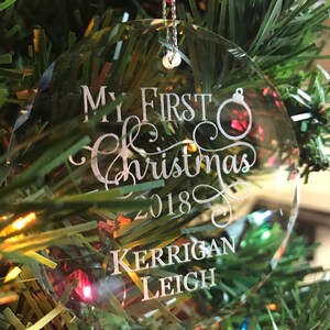 May include: Clear glass Christmas ornament with the text "My First Christmas 2018" and the name "Kerrigan Leigh" engraved on it.