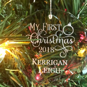 May include: Clear glass Christmas ornament with the text "My First Christmas 2018 Kerrigan Leigh" engraved in silver.