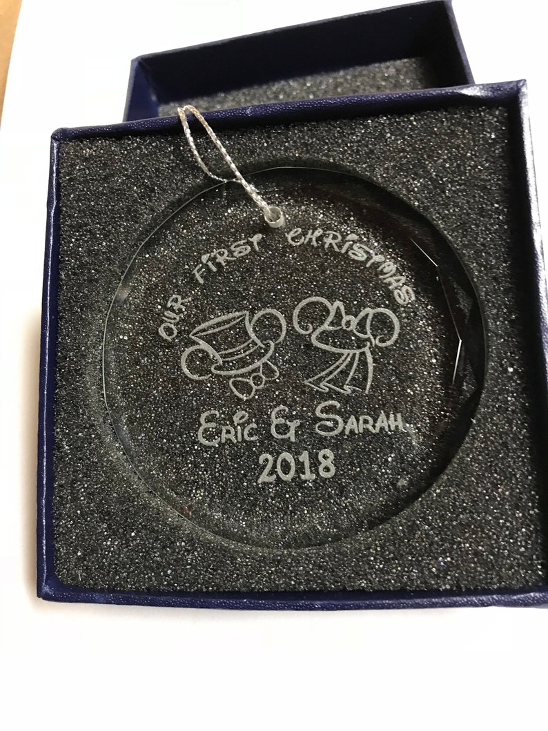 Pu&ograve; includere: Ornamento natalizio in vetro trasparente con design inciso, presentato in una scatola blu. L'ornamento recita "OUR FIRST CHRISTMAS" con personaggi di topi dei cartoni animati e i nomi "Eric & Sarah" e l'anno "2018".